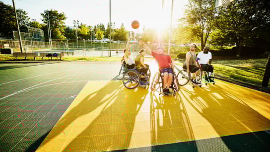 Adaptive athlete taking shot during wheelchair basketball game on outdoor court