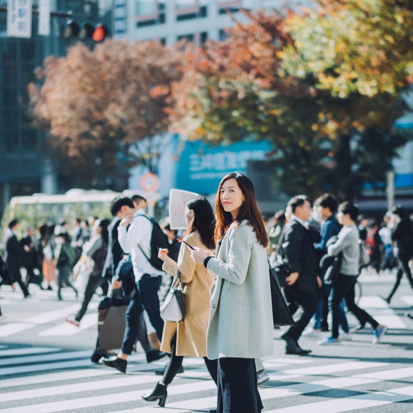 businesswoman using smartphone while walking on busy street in Tokyo.