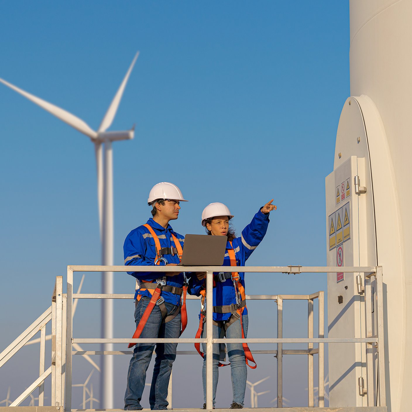 Maintenance engineers are checking wind turbines at wind power plant electric energy station
