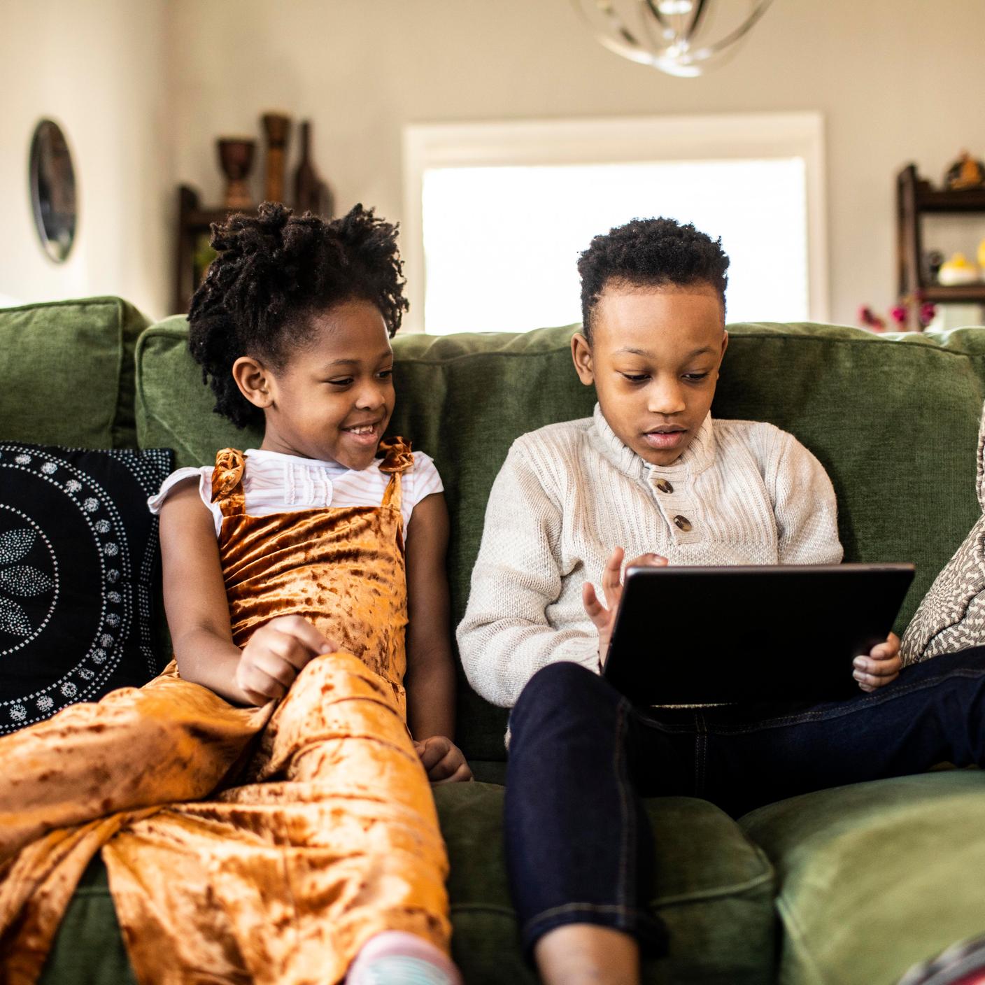 Brother and sister watching digital tablet on sofa at home