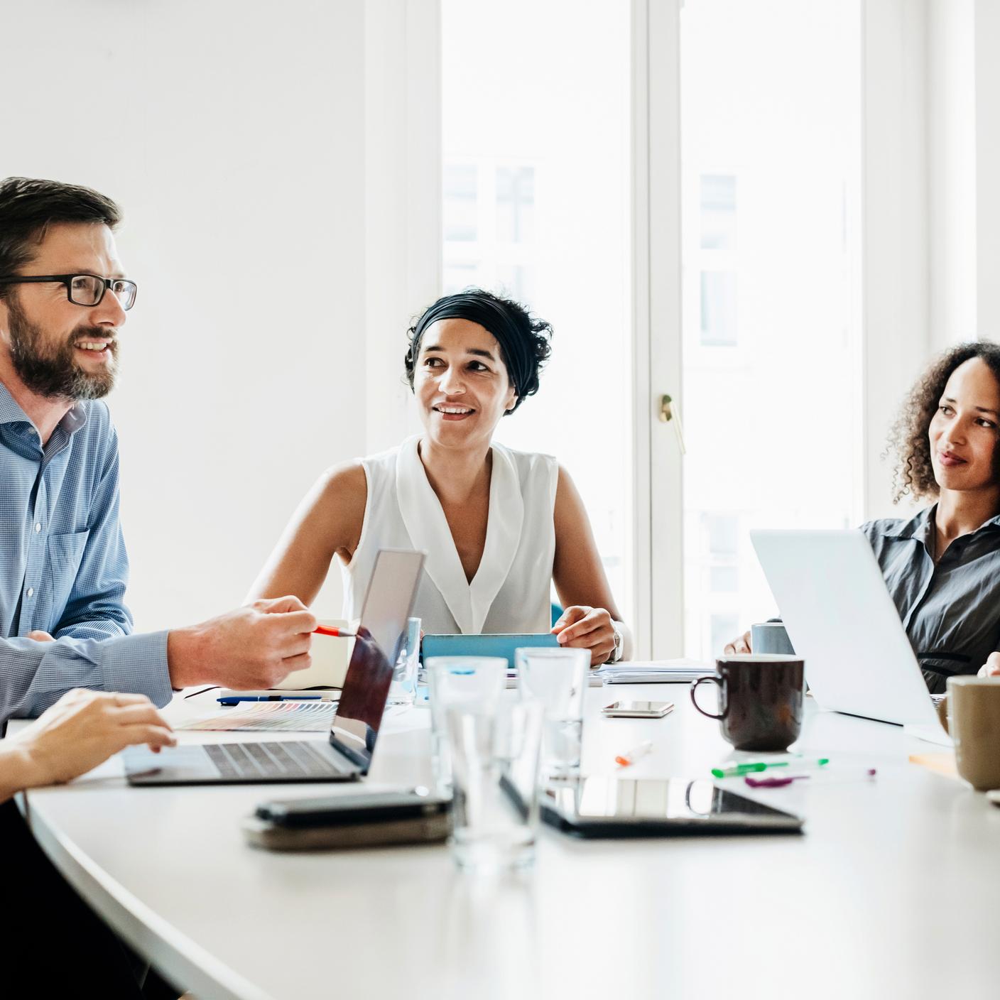 Four people around a desk with computers in front of them having a discussion