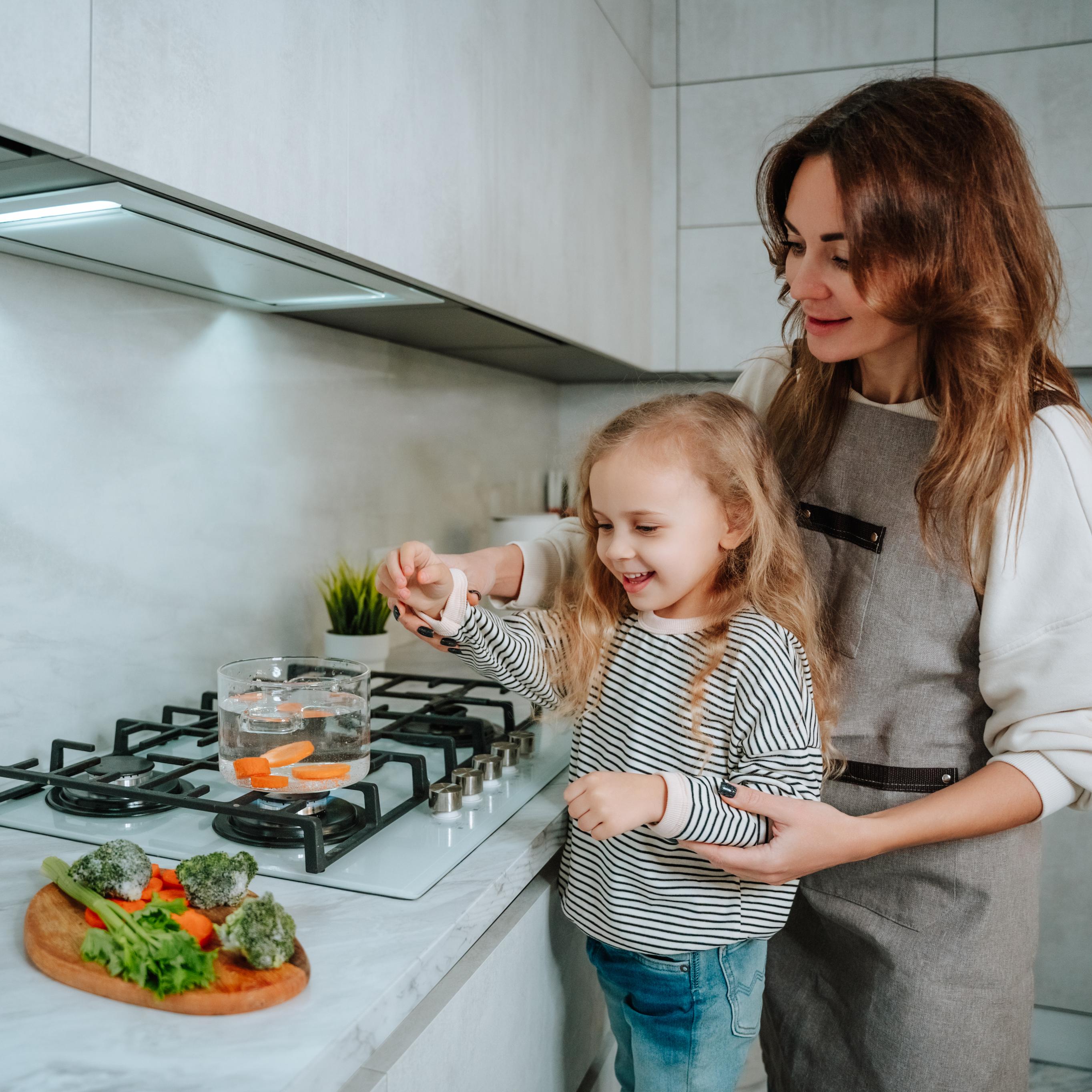 Mother and daughter using gas hob