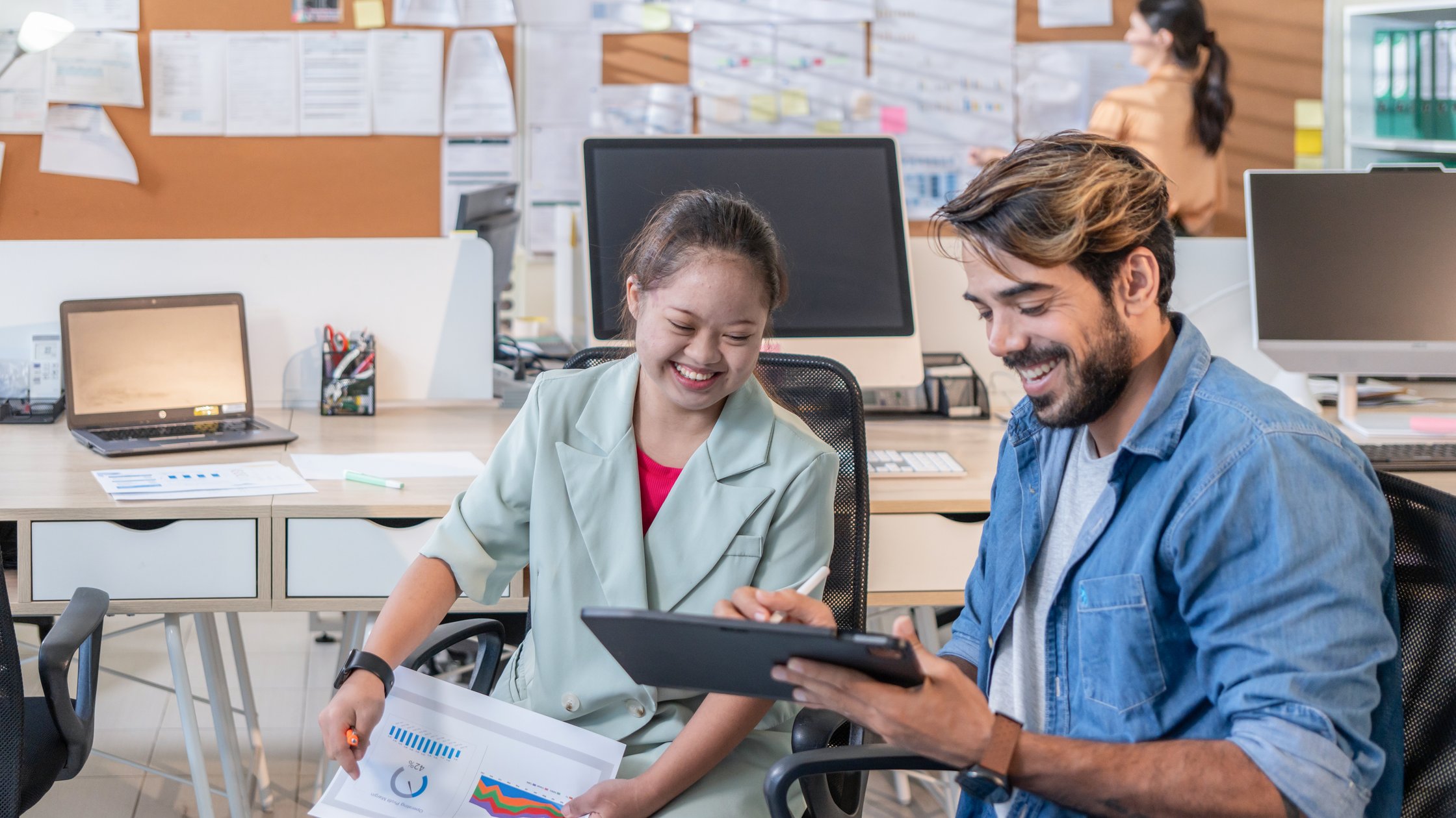 Young businesswoman working with her colleague in an office, social inclusion and cooperation concept.