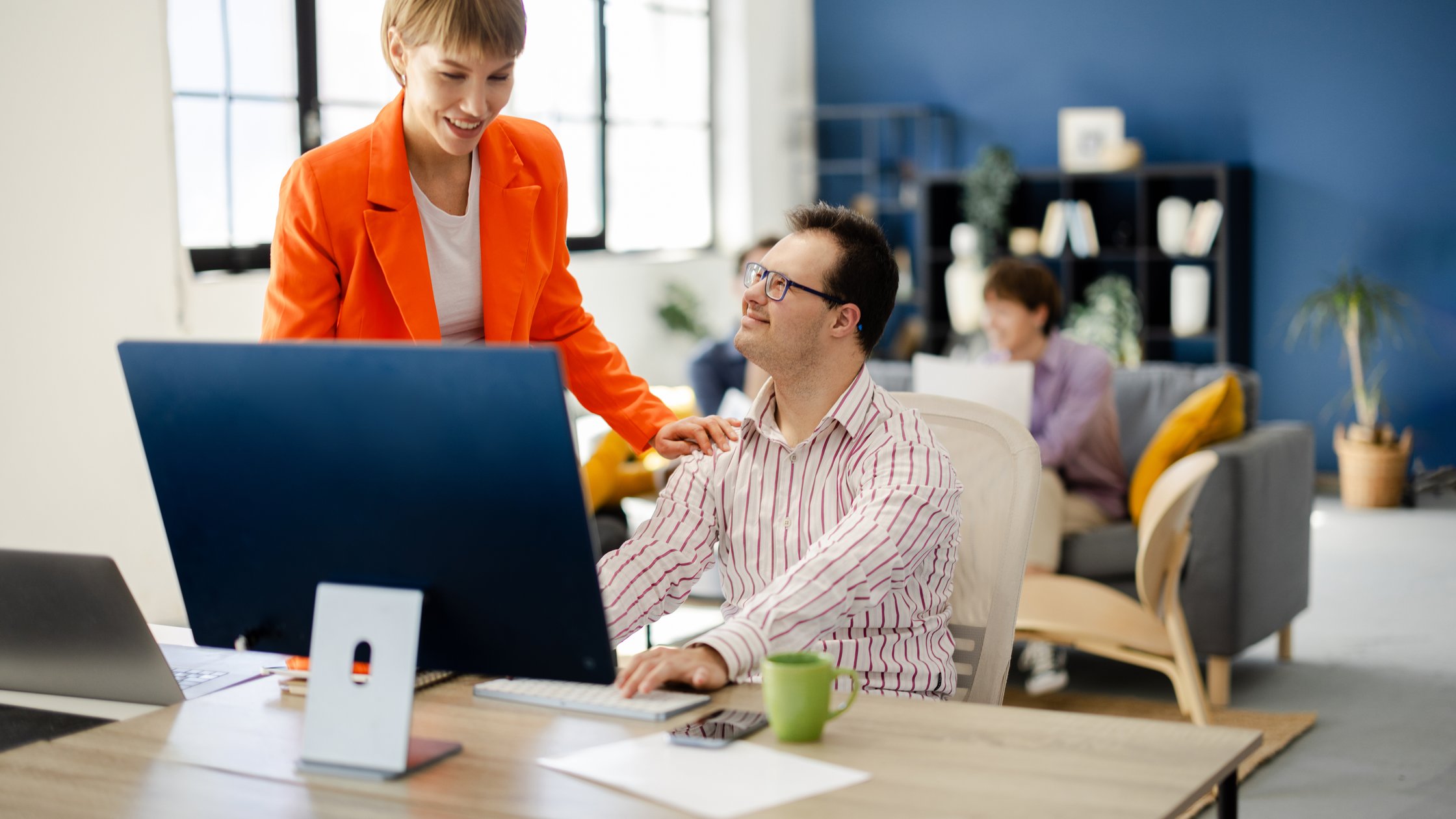 Female team manager working with her colleague with Down syndrome at their company office.