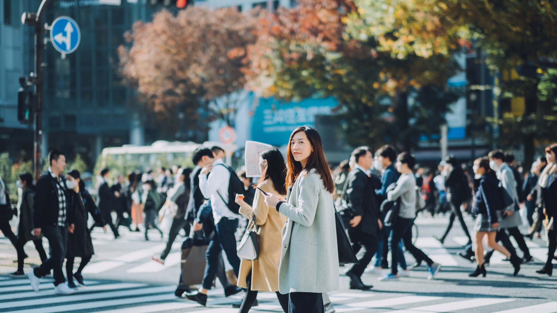 東京の賑やかな通りを歩きながらスマートフォンを使う美しいアジア人ビジネスウーマン