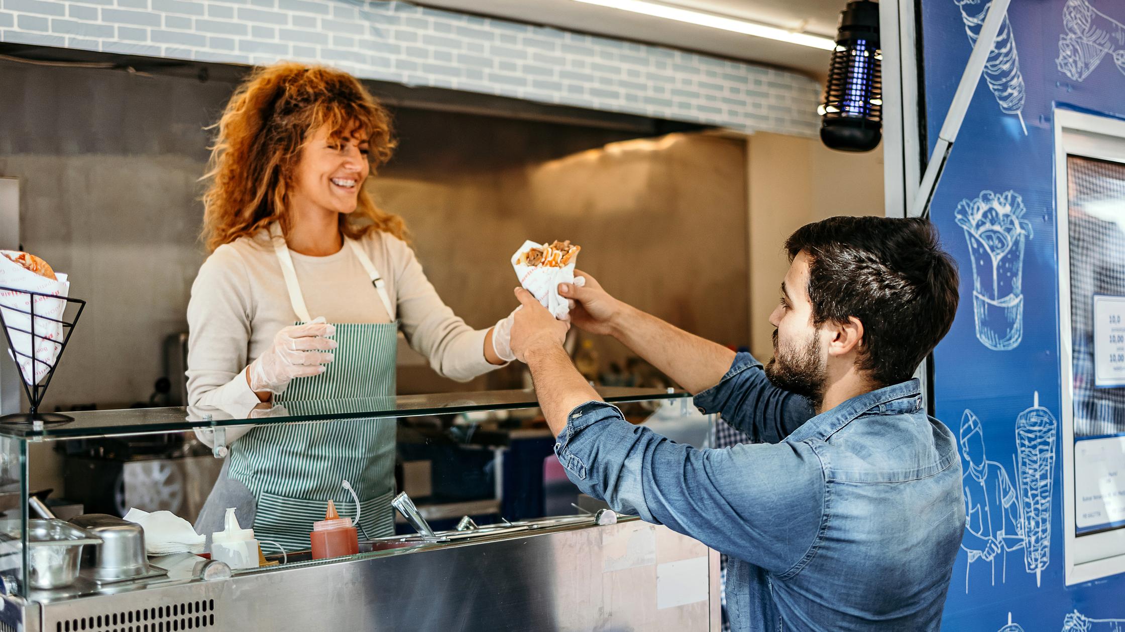 Una mujer vendiendo comida a un hombre en un camión.