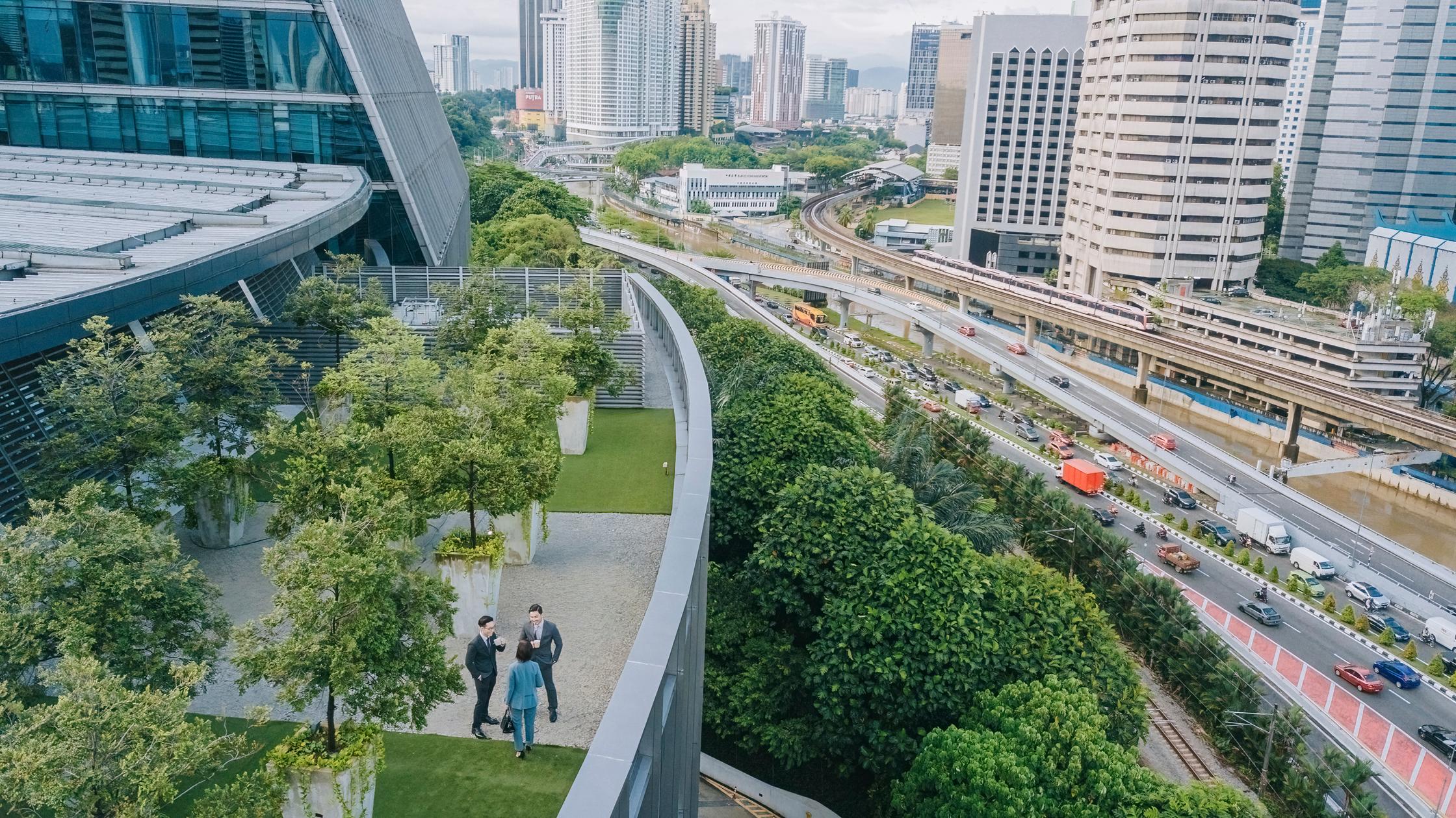 Three business professionals talking on roof top garden outside office building
